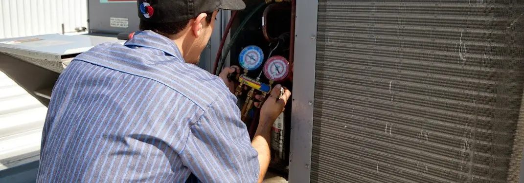 HVAC technician servicing a condenser unit in Kennett Square